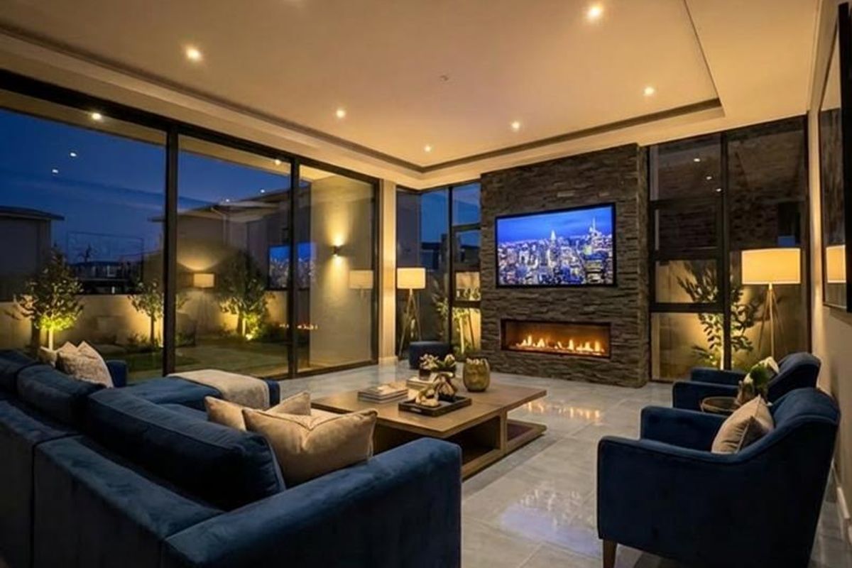 Modern living room featuring a stone-clad feature wall with a built-in fireplace, large format floor tiles, and expansive floor-to-ceiling glass doors.