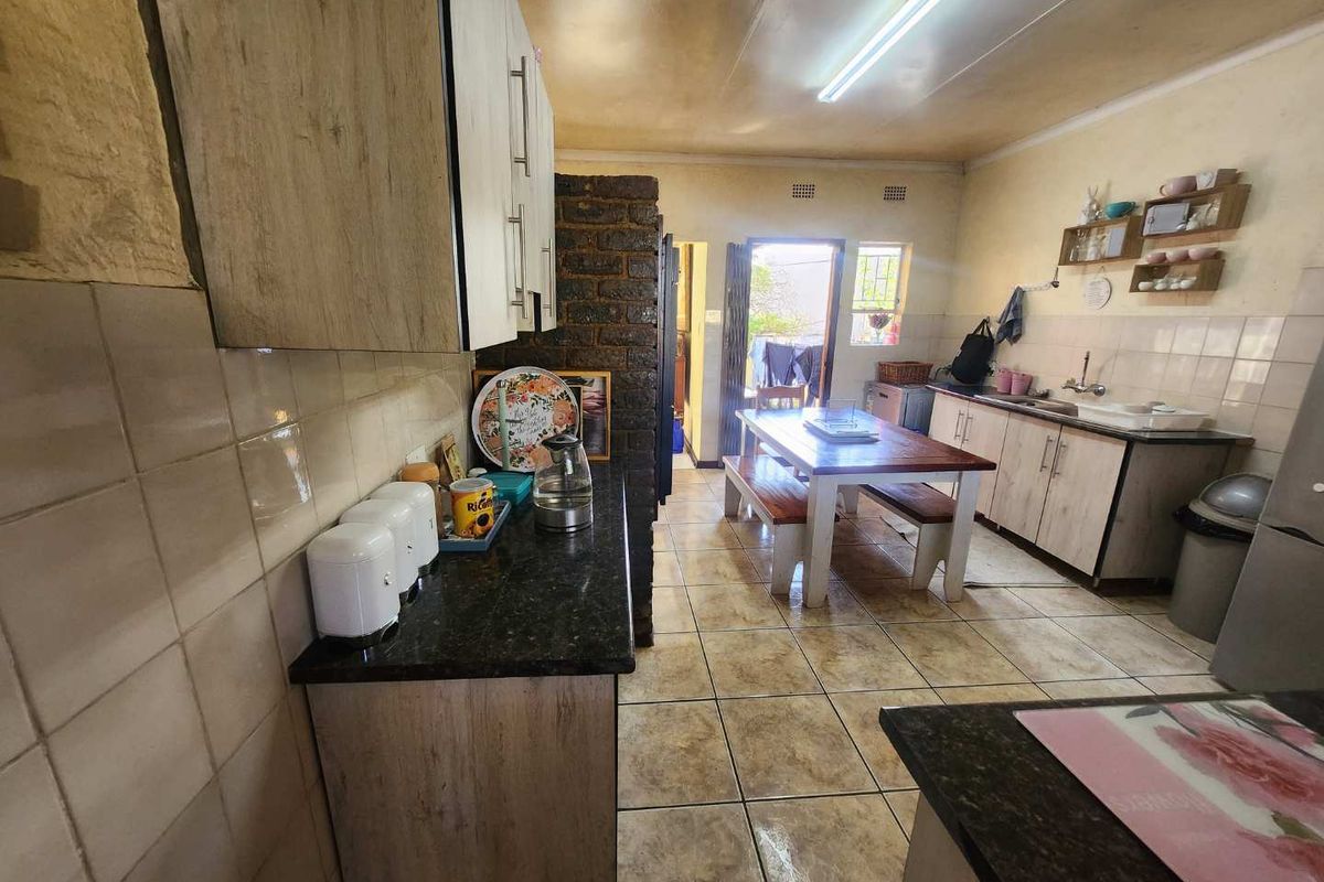 A functional kitchen featuring wood-look cabinetry, granite countertops, and tiled flooring, with direct access to an outdoor area.