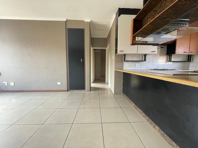 Open plan living and kitchen area featuring tiled flooring, built-in cabinetry, and a breakfast counter, offering a functional layout ready for modern updates.