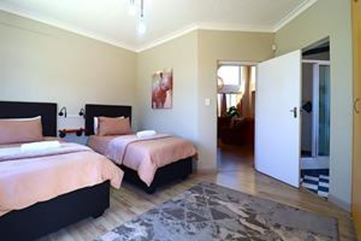 A bedroom featuring light-toned laminate flooring, neutral walls, and an en-suite bathroom access point.