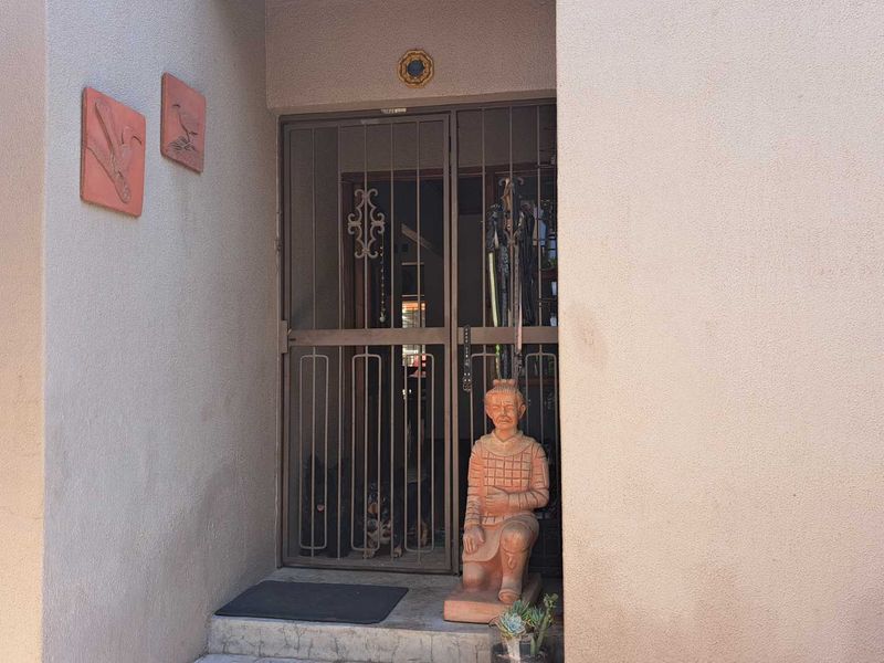 A residential entrance featuring a metal security gate and a concrete step, providing a secure access point to the home.