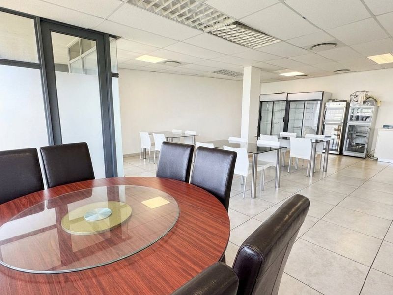 Open-plan commercial space featuring tiled flooring, suspended ceilings with recessed lighting, and integrated commercial refrigeration units, suitable for dining or office use.
