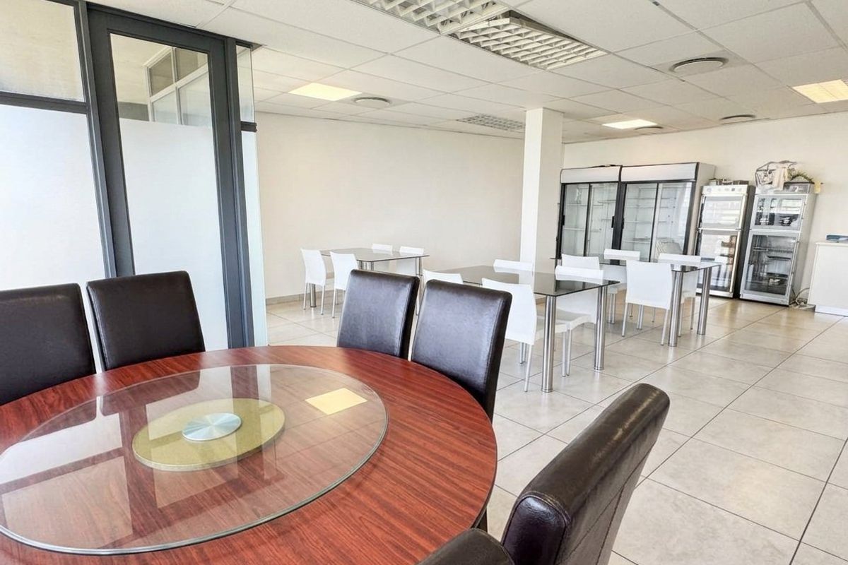 Open-plan commercial space featuring tiled flooring, suspended ceilings with recessed lighting, and integrated commercial refrigeration units, suitable for dining or office use.