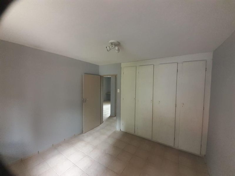 An empty bedroom featuring tiled flooring and built-in cupboards, offering a blank canvas for personalization.