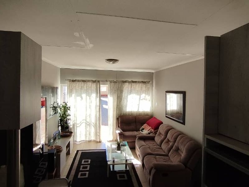 A living room featuring tiled flooring and a sliding glass door providing natural light and access to the exterior.