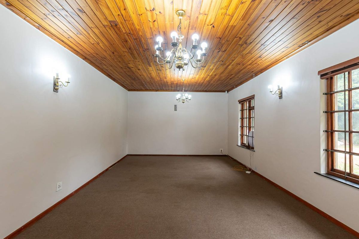 Spacious living area featuring a timber tongue and groove ceiling, classic chandelier lighting, and large windows with security bars.