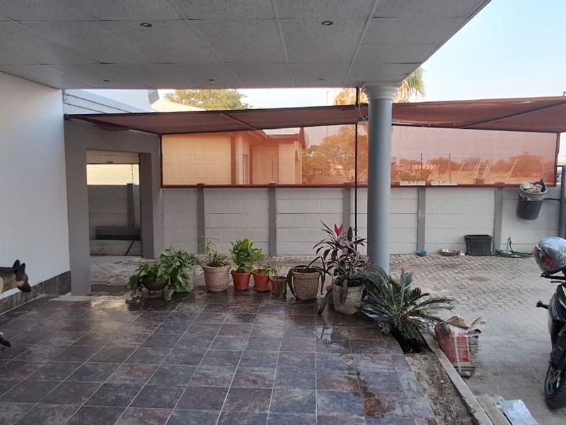 A covered patio area featuring tiled flooring, a support column, and perimeter walling, providing a functional outdoor space for relaxation.