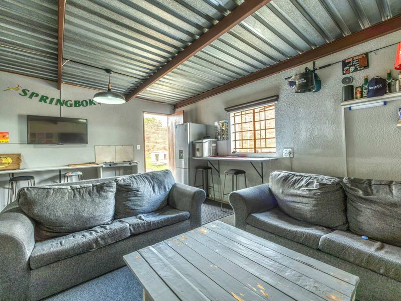 Casual living area featuring an industrial-style exposed corrugated metal roof, steel beams, and a built-in counter space with direct access to the exterior.