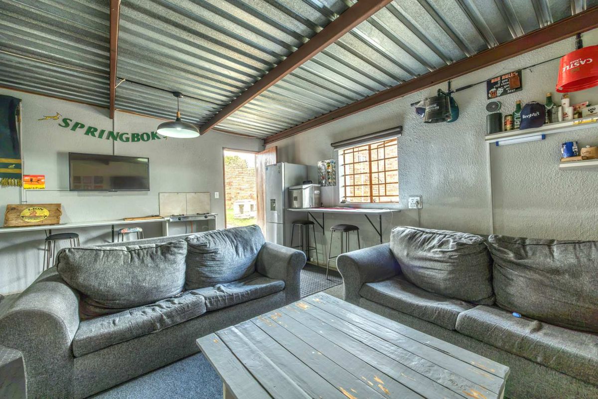 Casual living area featuring an industrial-style exposed corrugated metal roof, steel beams, and a built-in counter space with direct access to the exterior.