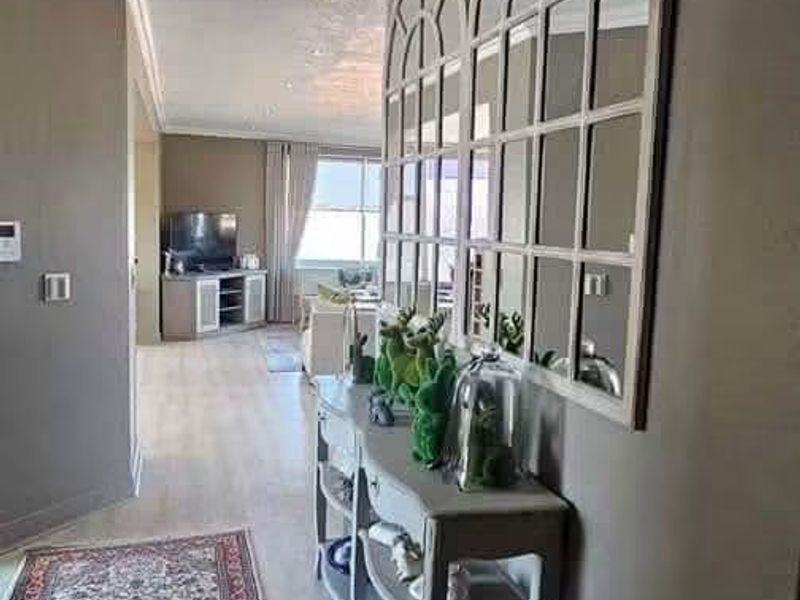 A well-maintained hallway featuring crown molding, recessed lighting, and light-toned laminate flooring, leading into the main living area.