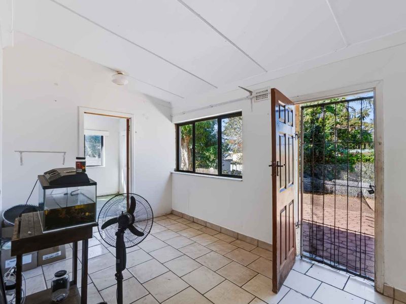 An entry area featuring tiled flooring, a security gate, and direct access to the exterior, offering a functional space with potential for cosmetic updates.
