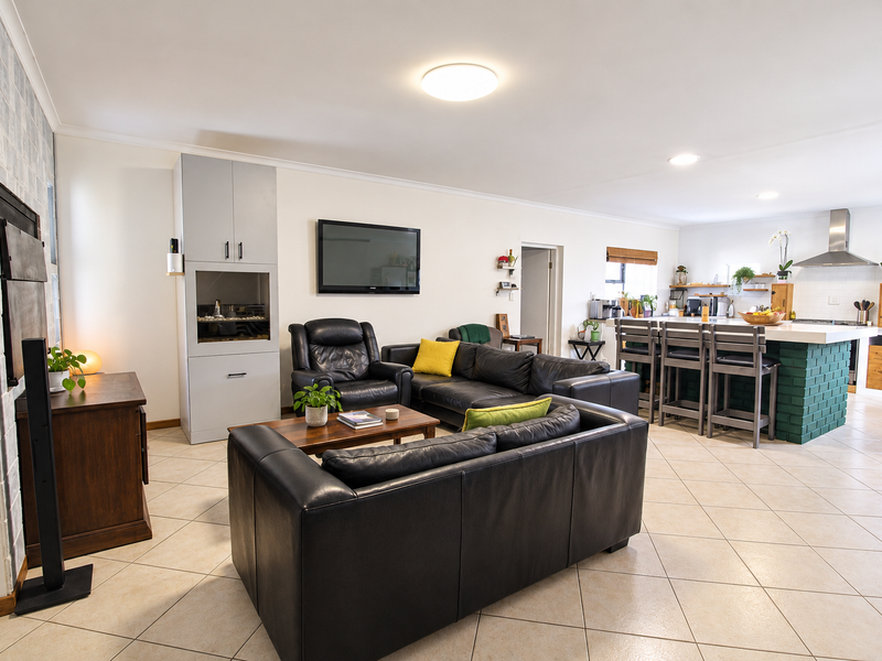 Spacious open-plan living area featuring a modern kitchen with a central island, tiled flooring, and a cozy fireplace, creating a functional and inviting space.