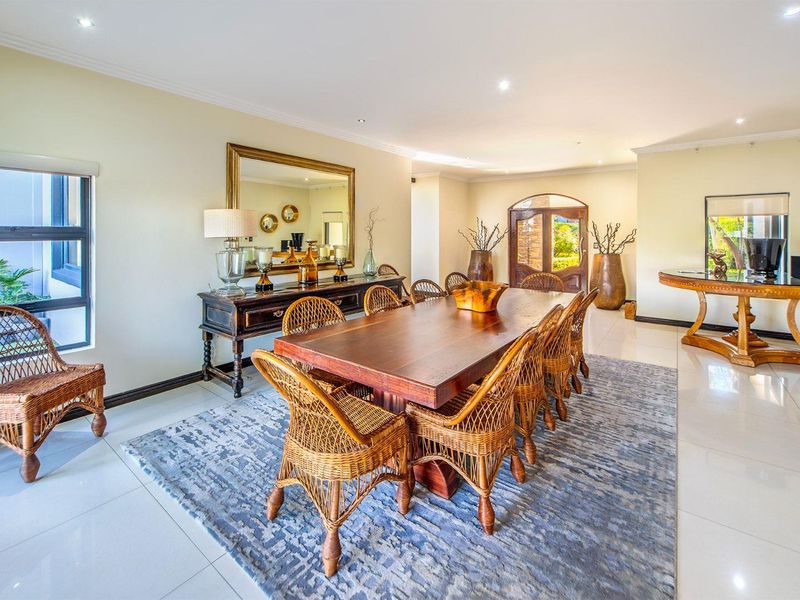 Spacious dining room featuring polished tiled flooring, recessed downlighting, and an elegant arched timber entrance door, creating a bright and inviting atmosphere.