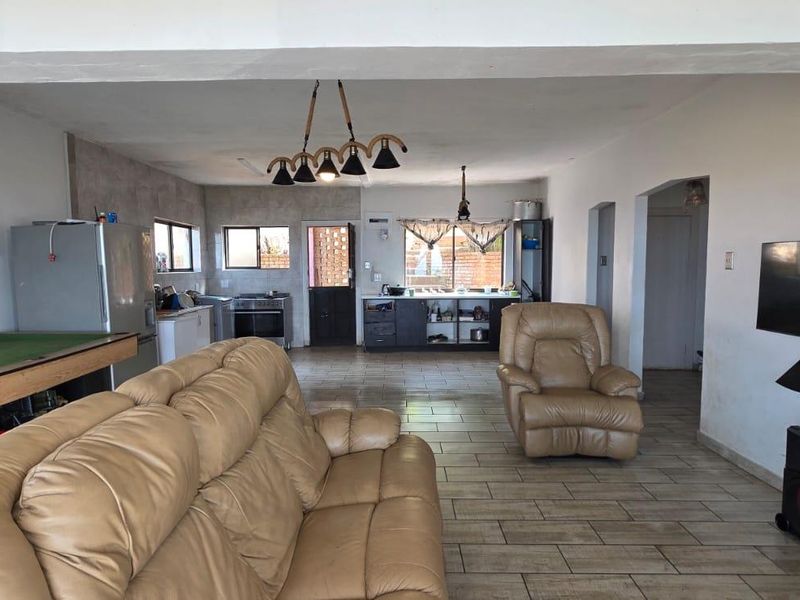 Spacious open-plan living and kitchen area featuring tiled flooring, functional cabinetry, and a neutral layout suitable for modern updates.