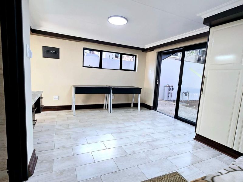 A bright, open-plan living space featuring modern tiled flooring, built-in storage cabinetry, and a sliding glass door providing direct access to the exterior.