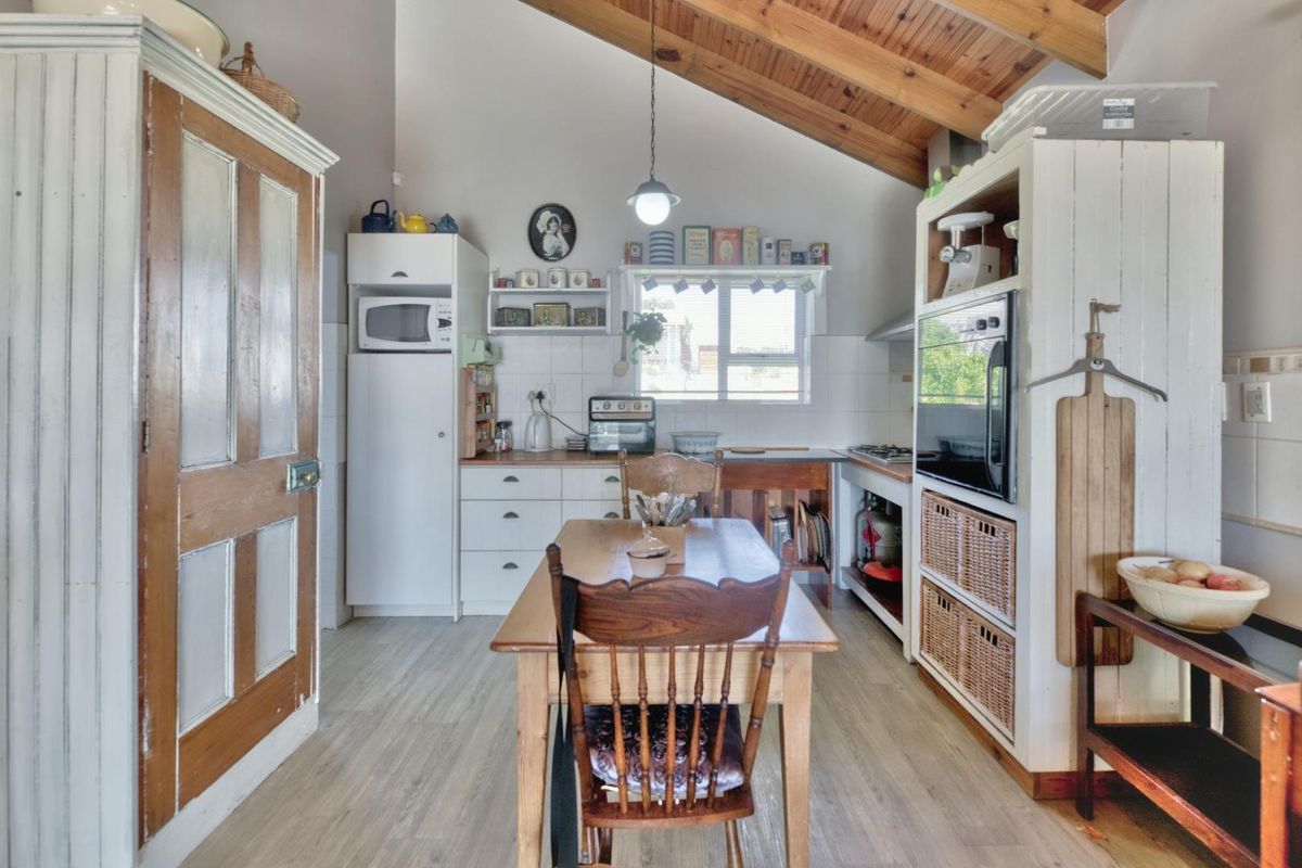 A rustic kitchen featuring timber vaulted ceilings, built-in cabinetry, integrated oven, and a tiled splashback, offering a cozy and functional cooking space.
