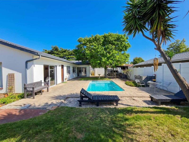 A well-maintained outdoor pool area featuring a paved patio, swimming pool, and direct access to the home through sliding glass doors.