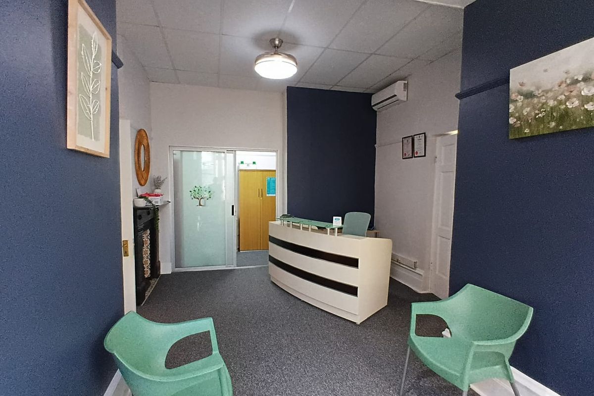 A professional reception area featuring a built-in desk, split-system air conditioning, and a sliding glass door leading to an adjacent office space.