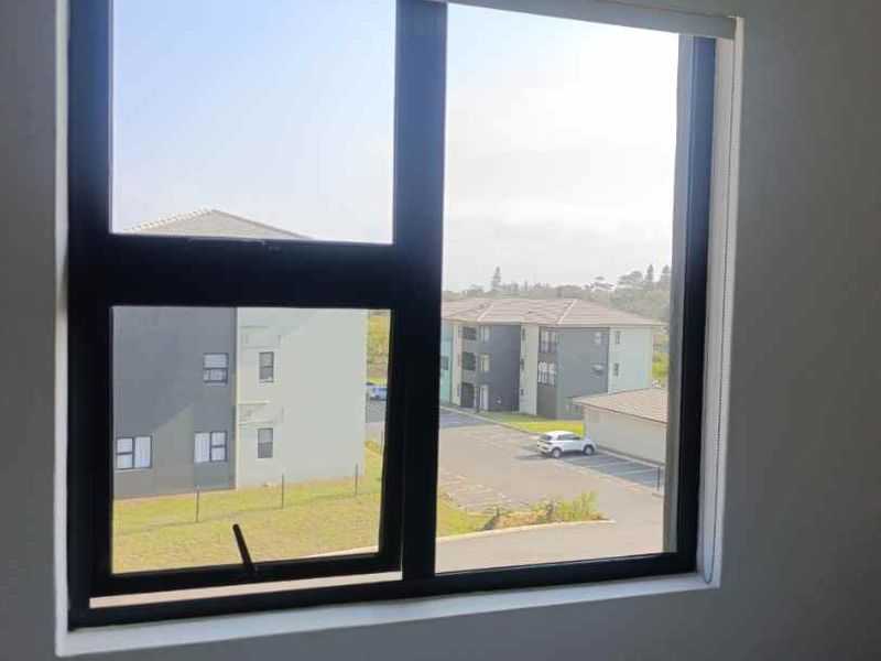 A view from an interior window looking out over the apartment complex parking area and surrounding buildings.