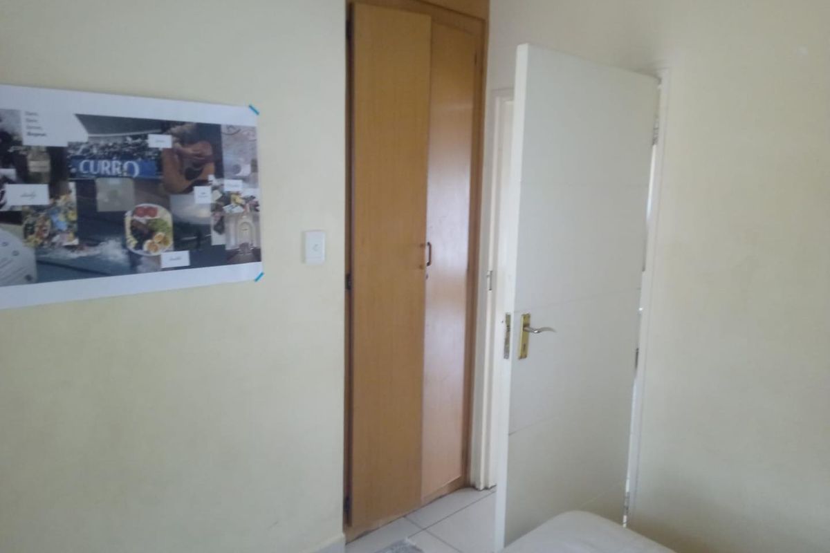 A bedroom interior featuring built-in wooden cupboards and a standard door, providing functional storage space.