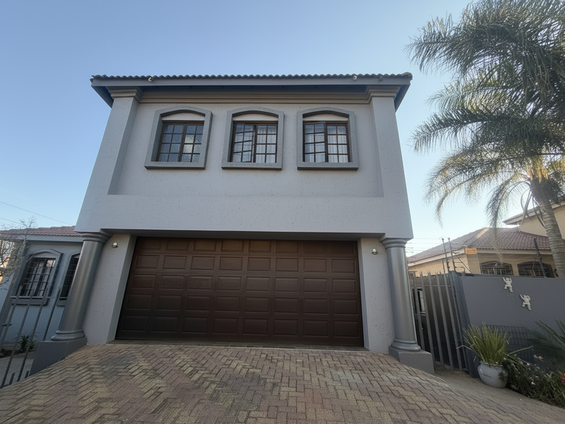 Front elevation of a two-story residence featuring a double garage, paved driveway, and decorative architectural columns.