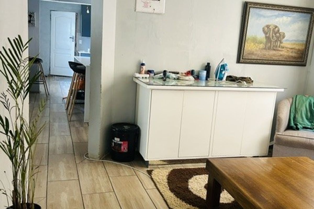 Living room area featuring tiled flooring and an exposed electrical distribution board, with visible ceiling damage requiring repair.