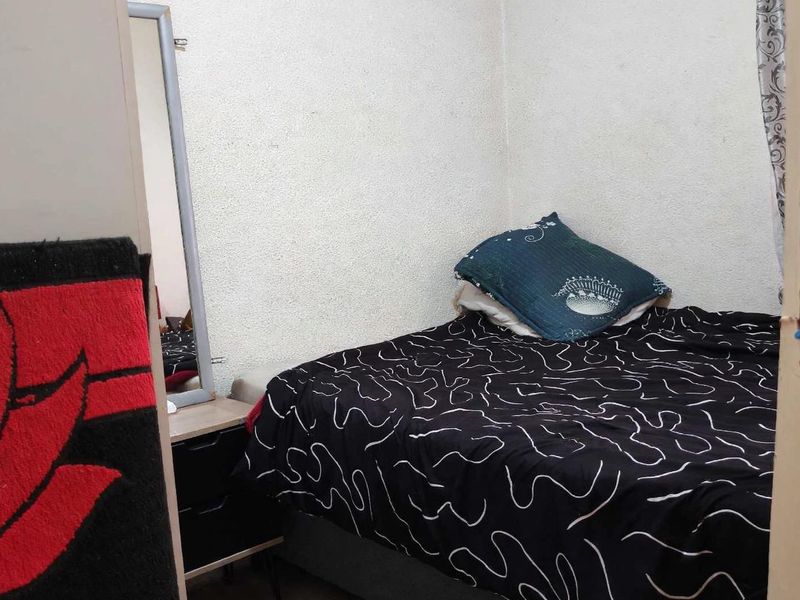 A compact bedroom space featuring textured wall finishes and a standard door entry.