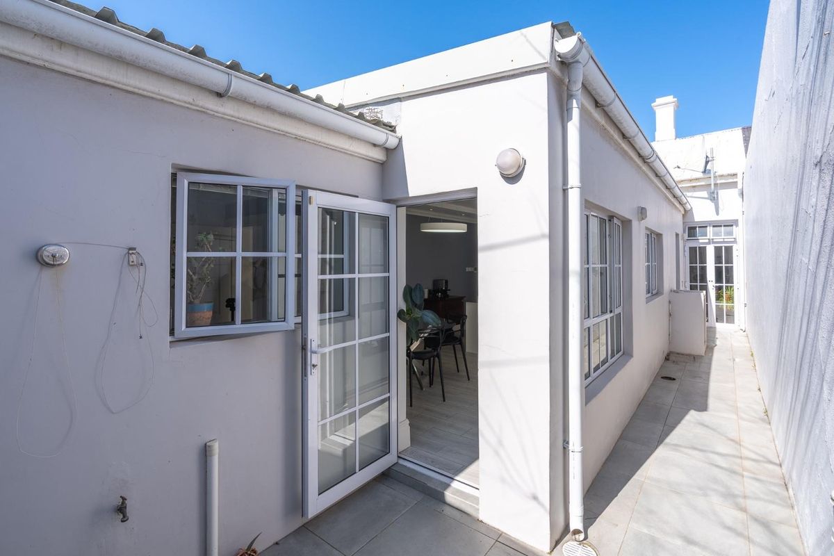 A view of the rear exterior showing a tiled patio area, white painted walls, and access through french doors into the home.