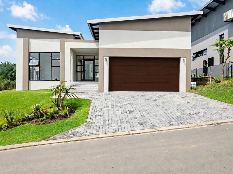 Modern contemporary house exterior featuring a paved driveway, double garage, and clean architectural lines with landscaped front garden.