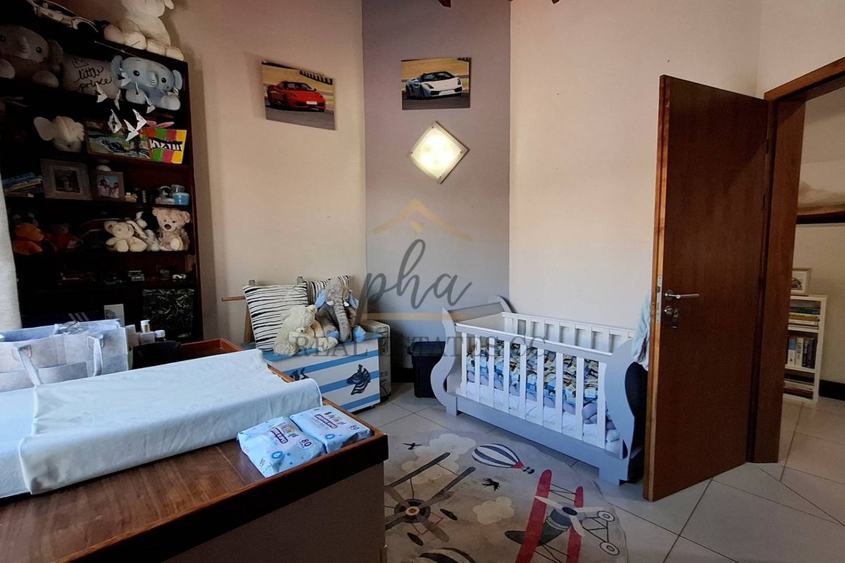 A functional bedroom featuring tiled flooring and a neutral wall finish, currently utilized as a nursery.