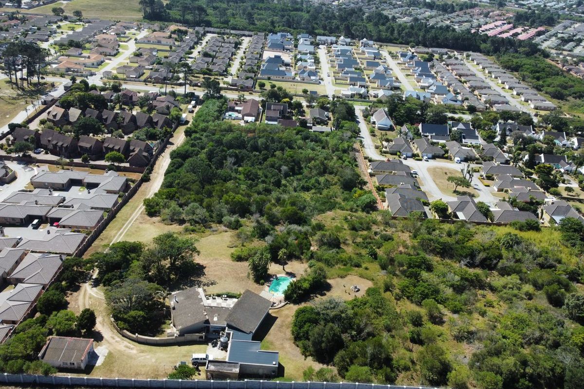 Aerial view of a residential property featuring a swimming pool, surrounded by established vegetation and neighboring suburban housing developments.