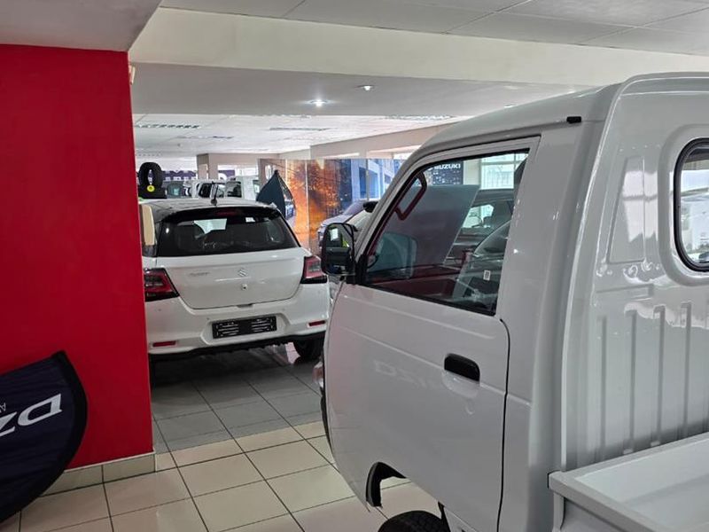 A spacious indoor showroom or garage area featuring tiled flooring and a suspended ceiling, currently utilized for vehicle display.