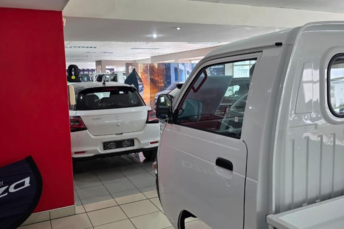 A spacious indoor showroom or garage area featuring tiled flooring and a suspended ceiling, currently utilized for vehicle display.