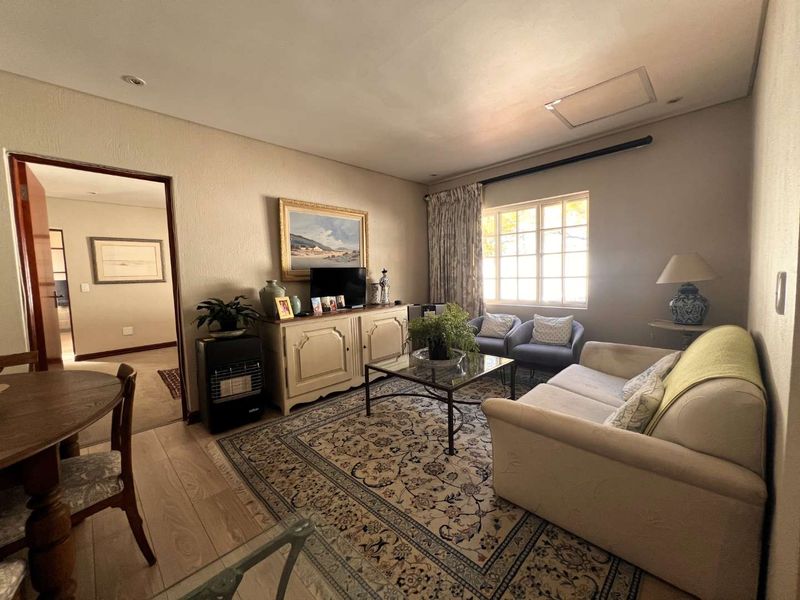 A comfortable living room featuring laminate flooring, recessed ceiling lighting, and a large window, providing a functional and inviting space.