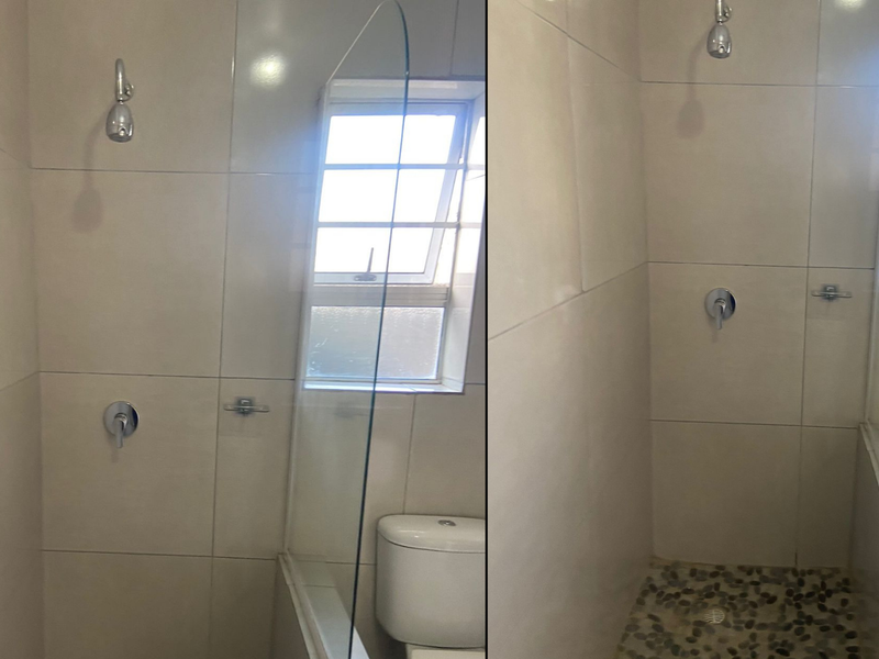 A bathroom featuring a shower with a glass screen, pebble floor detailing, and a toilet.