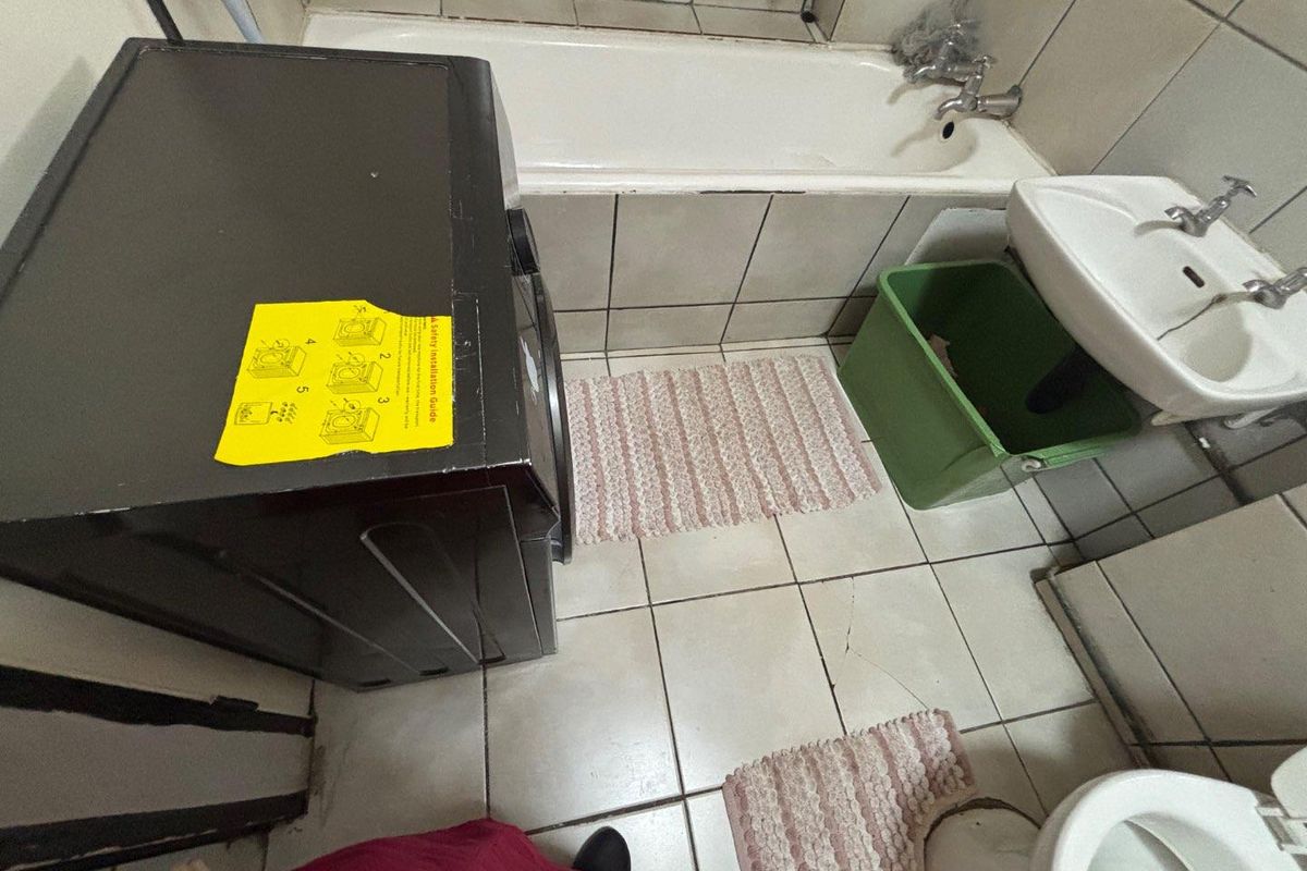 A compact bathroom featuring a bathtub, pedestal basin, and toilet with dated ceramic tiling throughout.