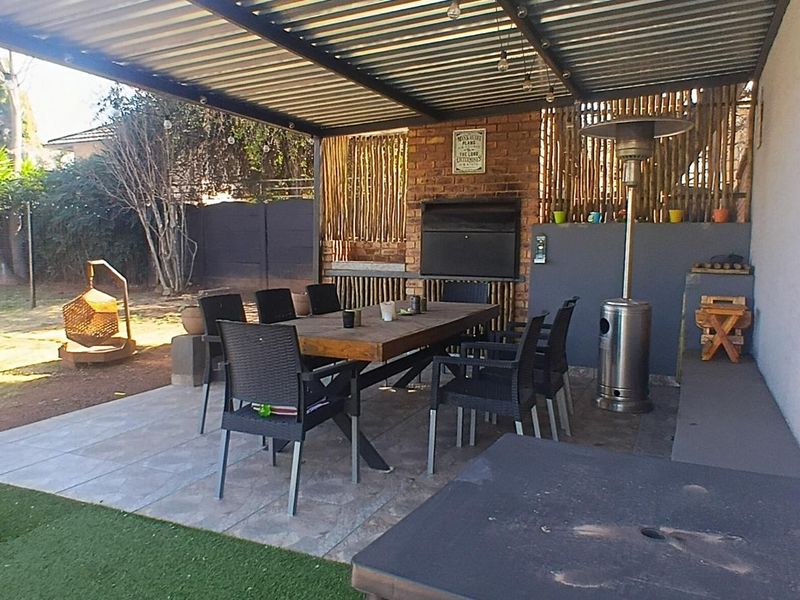 Covered outdoor patio area featuring a built-in braai, tiled flooring, and a corrugated metal roof, perfect for alfresco dining and entertaining.