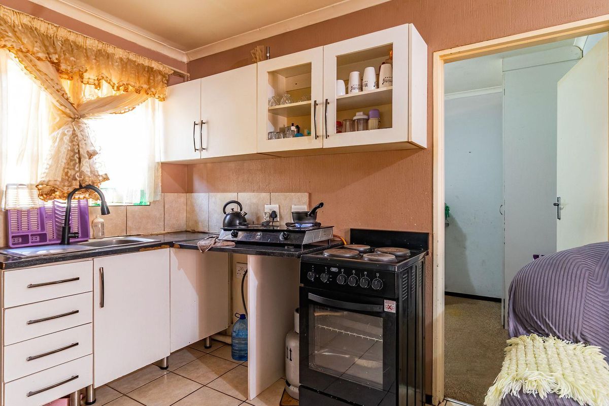 A compact kitchen featuring built-in cabinetry, a tiled backsplash, and a freestanding stove, offering a functional layout with potential for modern updates.