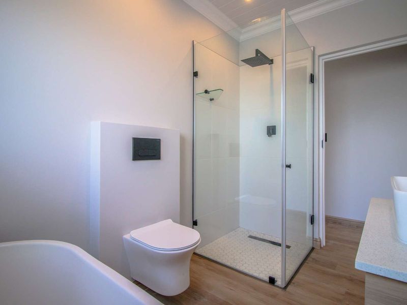 Modern bathroom featuring a sleek glass shower enclosure, wall-hung toilet, freestanding bathtub, and a contemporary vessel sink vanity.