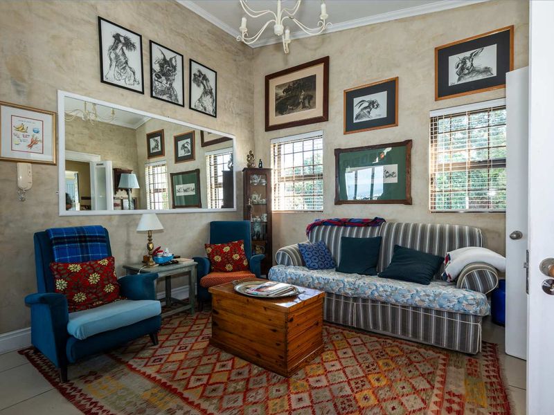 A cozy living room featuring tiled flooring, large wall-mounted mirror, and multiple windows with fitted blinds, offering a comfortable and well-lit space.