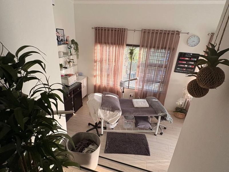 A well-maintained room currently utilized as a beauty treatment space, featuring light timber-look flooring, recessed downlighting, and a tongue and groove ceiling.