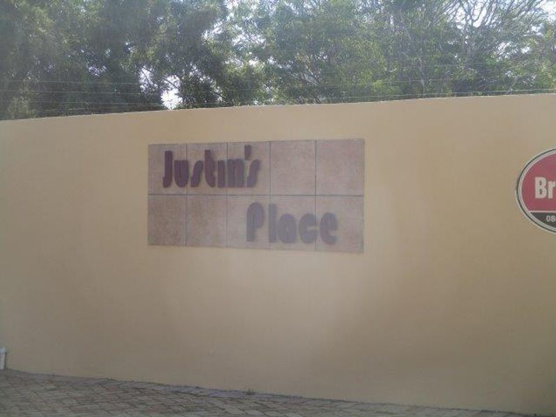 Exterior view of the property boundary wall featuring signage and electric fencing, situated along a paved driveway.
