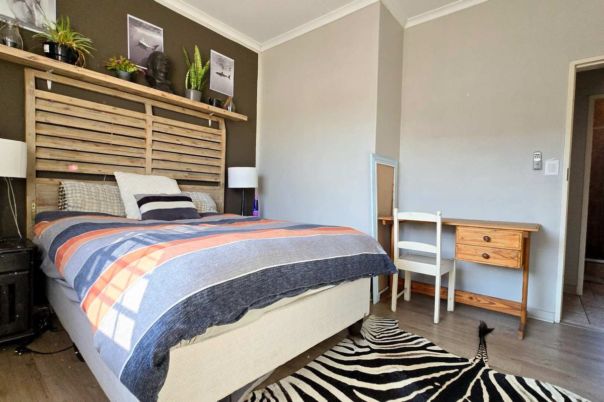 A bedroom featuring laminate flooring, a feature wall, and an adjoining en-suite bathroom.