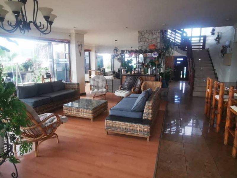 Spacious open-plan living area featuring a stone-clad feature wall, staircase, and a mix of laminate and tiled flooring with large sliding glass doors.