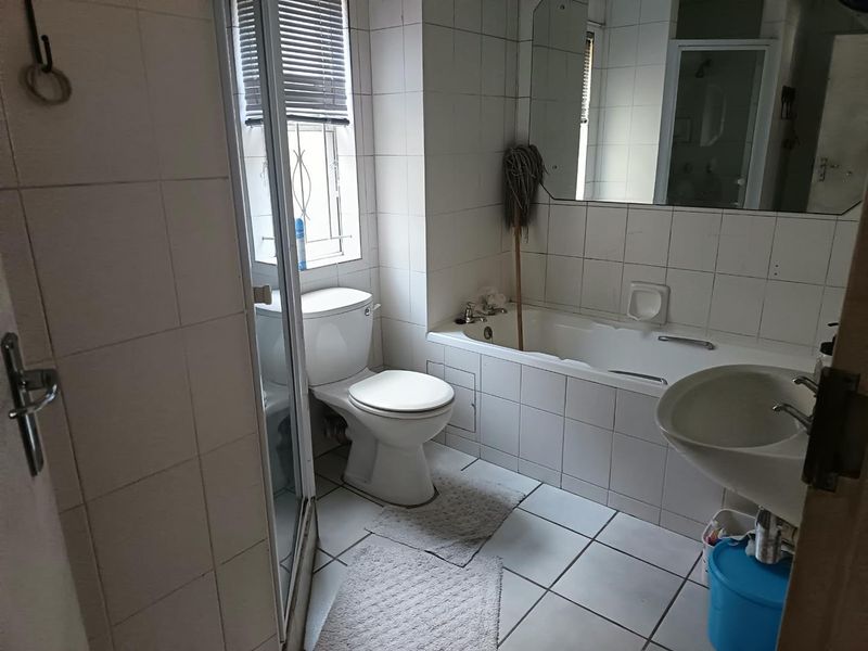 A dated bathroom featuring a built-in bathtub, pedestal sink, toilet, and a separate shower enclosure with white wall and floor tiling.
