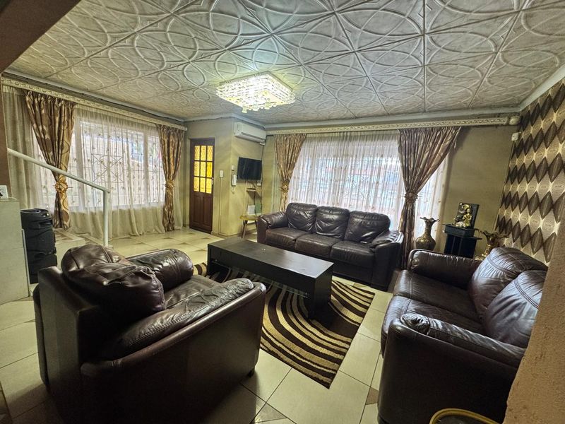 Spacious living room featuring tiled flooring, a decorative ceiling, and a split-system air conditioner, offering a comfortable and functional living space.