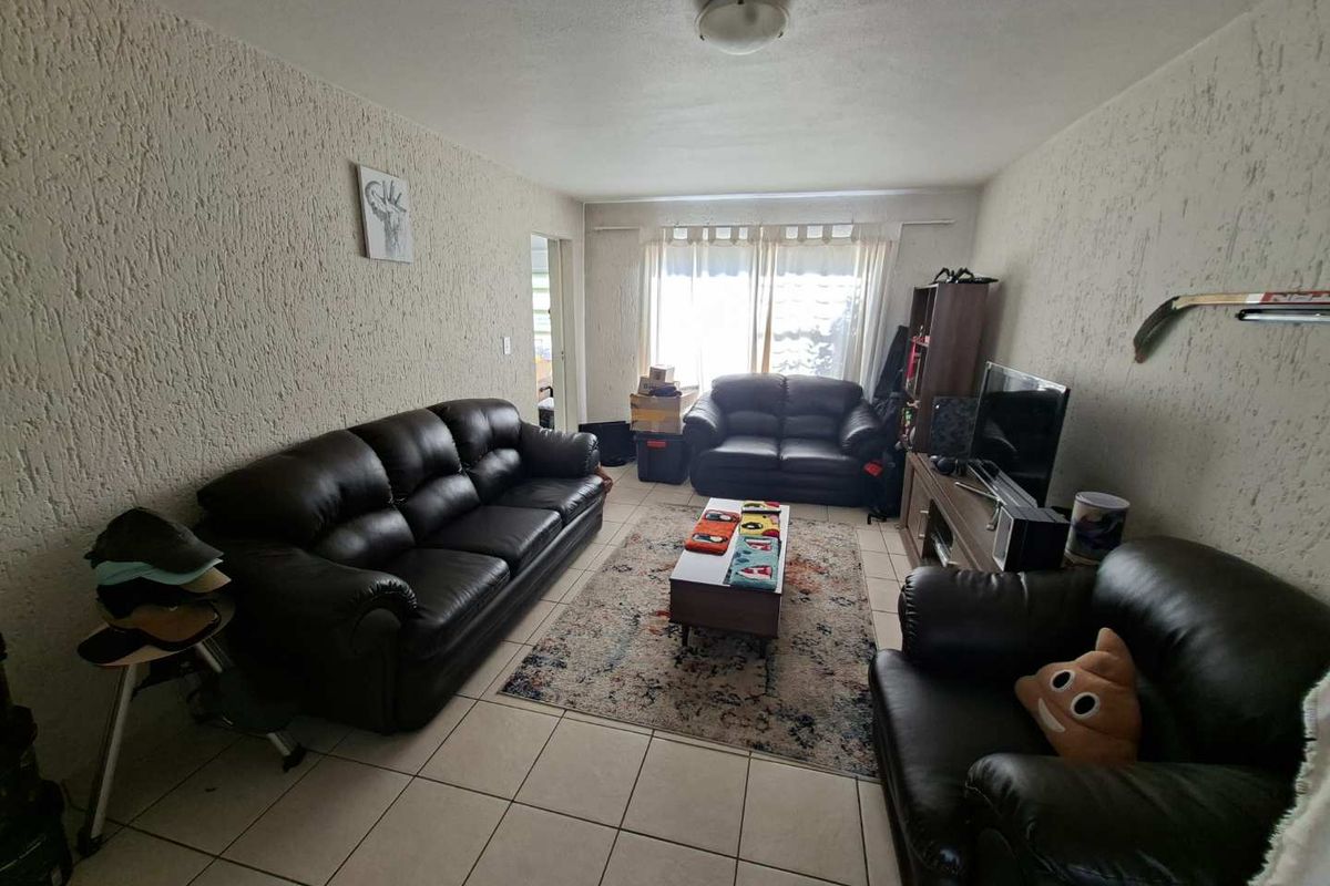 A living room featuring tiled flooring and textured wall finishes, providing a functional space for relaxation.