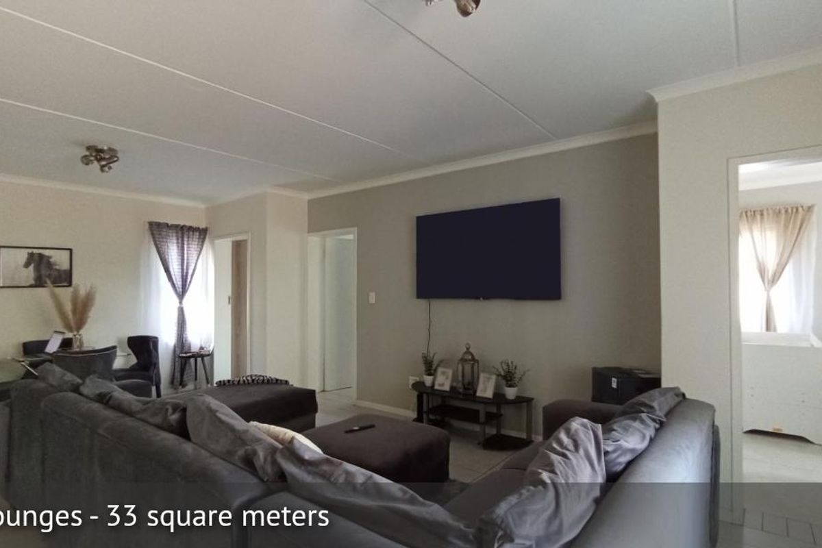 Spacious open-plan living area featuring neutral wall tones, tiled flooring, and access to adjacent rooms.