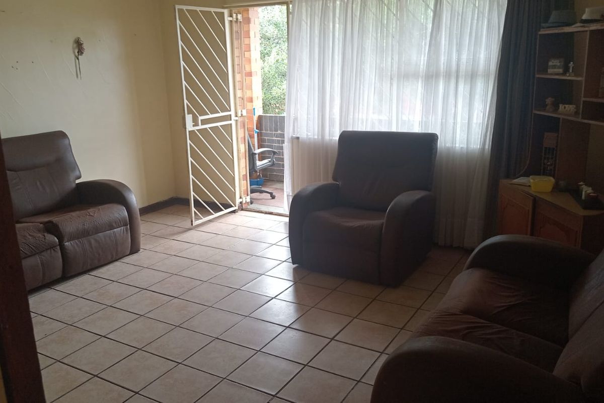 A living room featuring tiled flooring and a security gate leading to an outdoor balcony area.