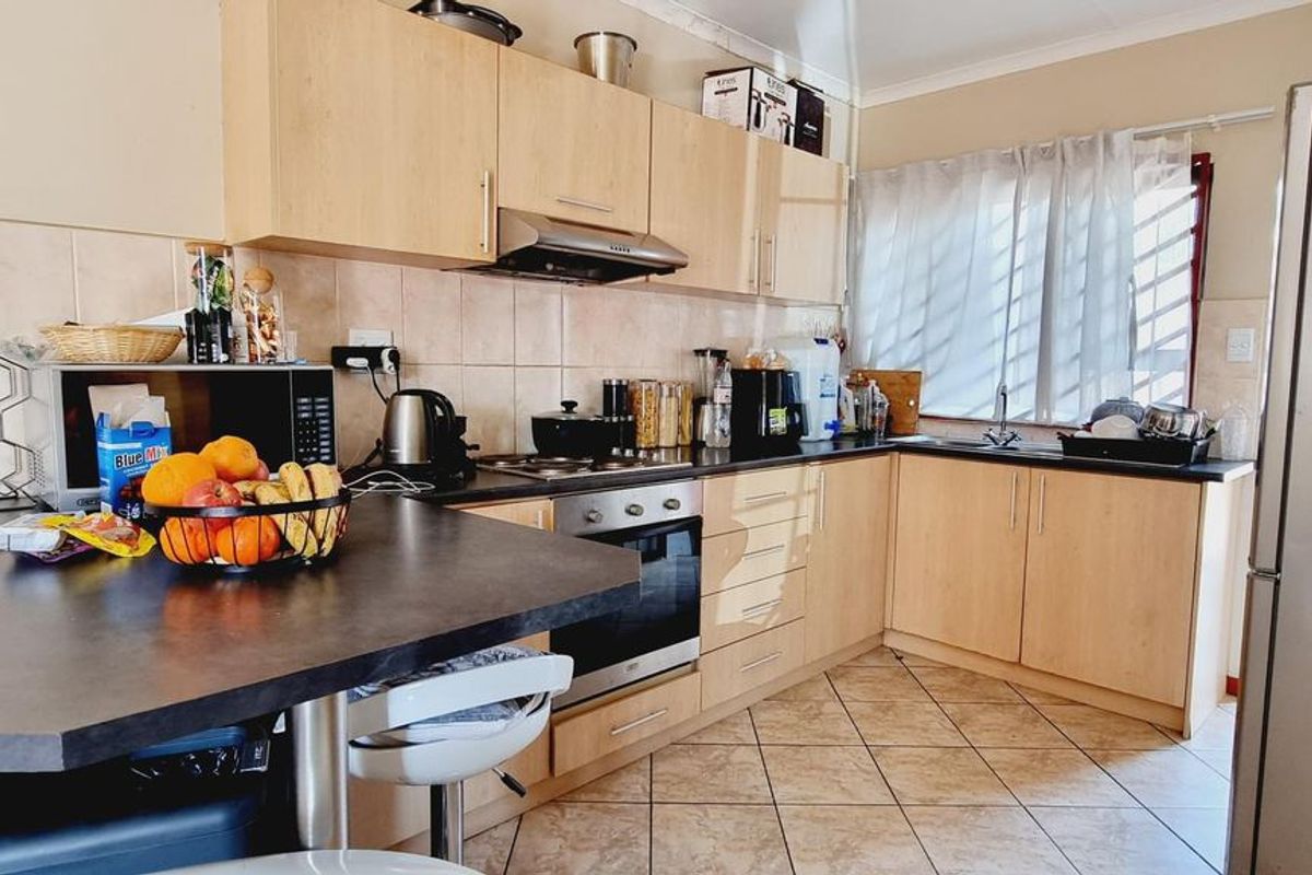 Functional kitchen featuring light wood-tone cabinetry, dark laminate countertops, built-in oven with extractor fan, and tiled flooring.